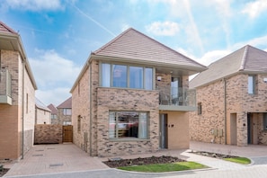 A modern residential building with a brick facade, large windows, and a balcony. - Stylish 4-br House - Free Parking Nice Garden (Oxford)