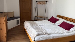 A bedroom with a wooden bed, a bench, a wardrobe, and a door. - Apartment in Fugen Near Spieljoch Cable Car (Fuegen)