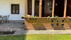 A wooden porch with flower planters and a stone patio. - Apartment in Fugen Near Spieljoch Cable Car (Fuegen)