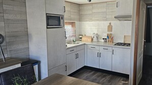 Une cuisine de taille réduite, équipée d’un four à micro-ondes, d’une cuisinière et de meubles de rangement en bois.