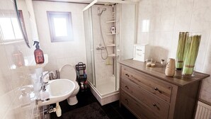 Une salle de bain équipée d’un lavabo, de toilettes, d’une douche et d’un meuble-lavabo.