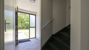 Un interior moderno con una escalera que lleva a un vidrio que da a un jardín.