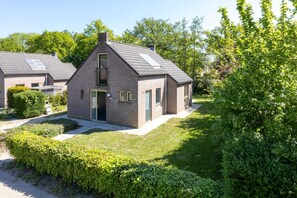 Et moderne hus i to etager med skråt tag, lille veranda og velholdt have.
