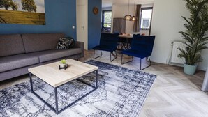 Una sala moderna con un sofá, una mesa de centro y un comedor con sillas.