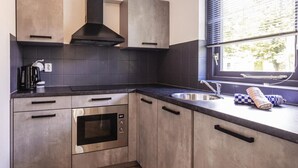 Una cocina moderna con horno integrado, un lavamanos y una ventana con persianas.