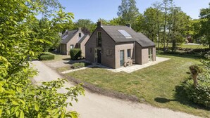 Una hilera de casas modernas de dos pisos con un patio central, rodeada de abundante follaje y árboles.