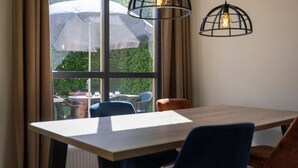 A dining area with a table and chairs, a window with curtains, and hanging pendant lights.