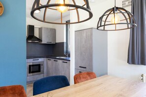 Eine moderne Küche mit grauen Schränken, einem eingebauten Ofen und einem Essbereich mit einem Holztisch und zwei Stühlen.