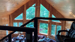 A wooden cabin interior with a sloped ceiling, large windows, and a view of the forest. - Lake Vermilion Cabin on a quiet bay with sauna & fire pit for grilling. (Cook)