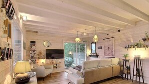 Una sala moderna con un sofá color beige, un televisor y una estantería.
