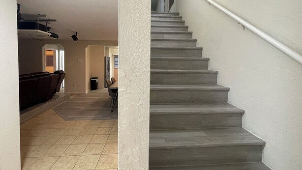 Una escalera con barandilla que sube a un piso superior.