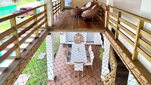 Un espacio al aire libre techado con techo de paja, barandillas de madera y piso con mosquiteras.
