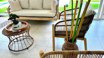 A modern living room with a sofa, wicker chairs, and a small table with a plant.