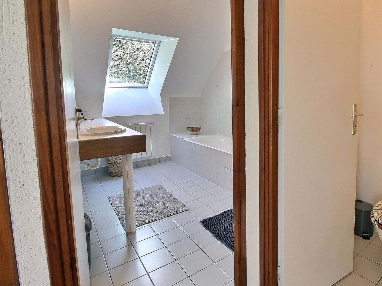 A bathroom with a skylight, a bathtub, a sink, and a toilet.