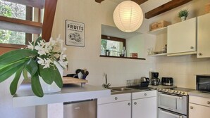 A modern kitchen with white cabinets, stainless steel appliances, and a wooden ceiling. - La Ferme rouge, Le Pin (PLUVIGNER)