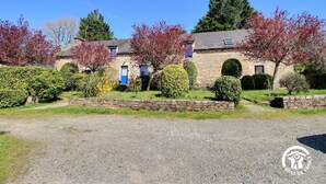 A stone building with multiple windows and a gravel driveway. - La Ferme rouge, Le Pin (PLUVIGNER)