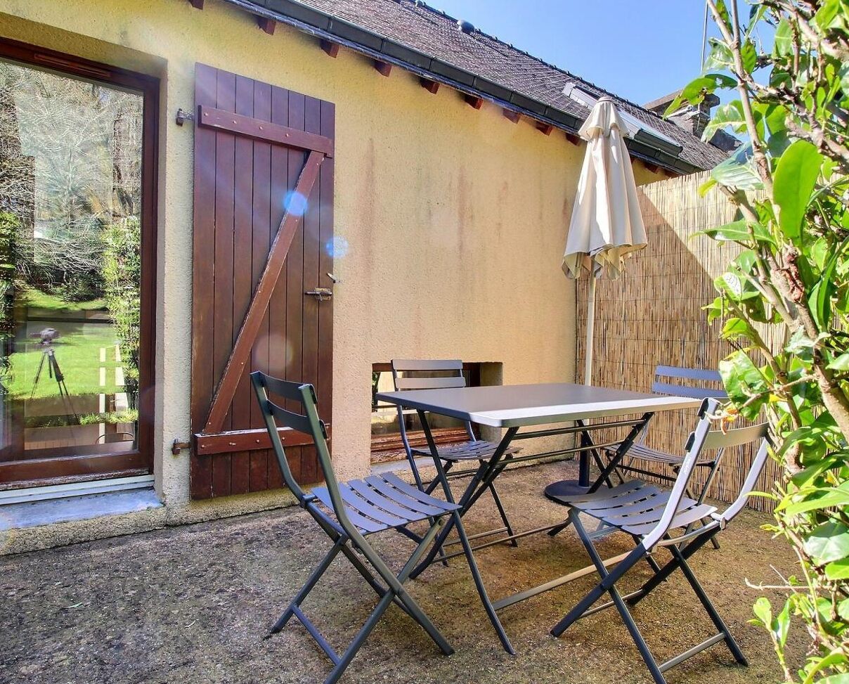 A patio with a table and chairs, a wooden door, and a bamboo fence.