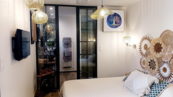 A bedroom with a bed, a television, and a sliding glass door leading to a bathroom.