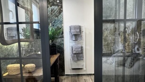 Ein modernes Badezimmer mit Marmorfliesenspiegel, einem Holzbadezimmerschrank und einem Handtuchhalter.
