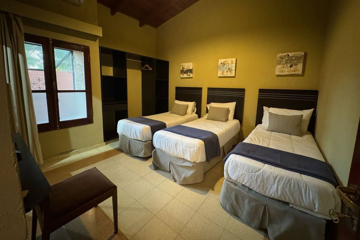 A bedroom with two beds, a bench, and a wardrobe.
