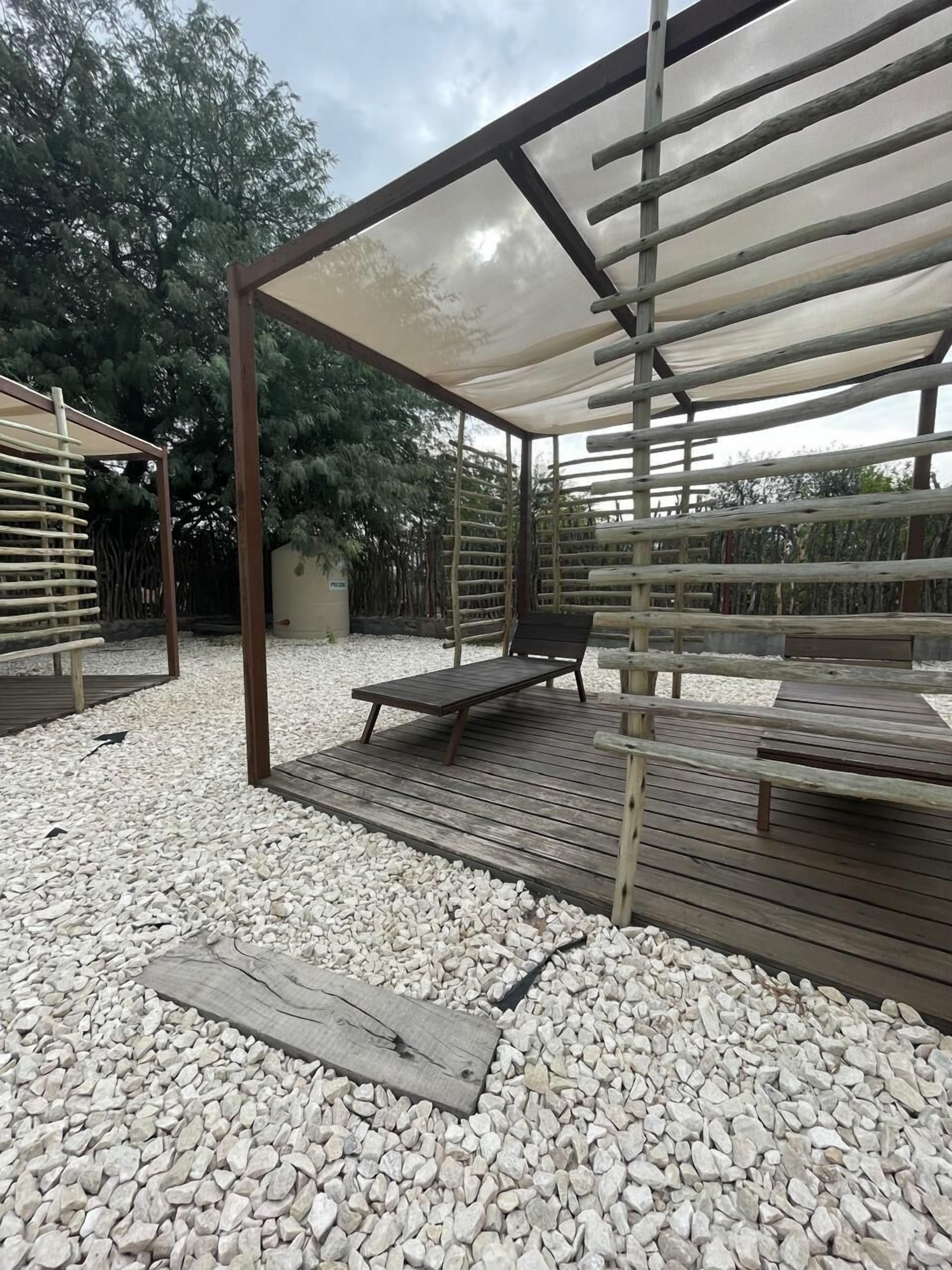 Un espace extérieur abrité, doté de bancs en bois et d’une structure en forme de pergola.