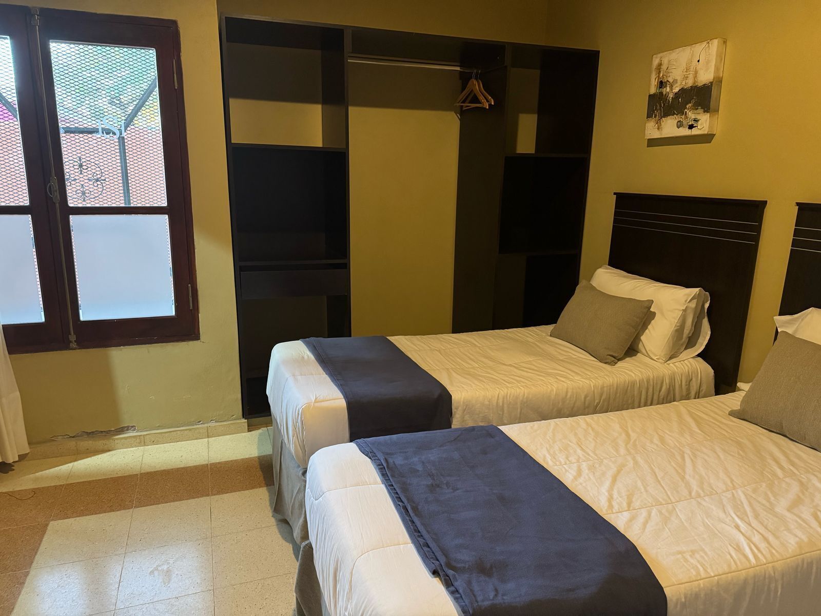 A hotel room with two beds, a wardrobe, and a window.