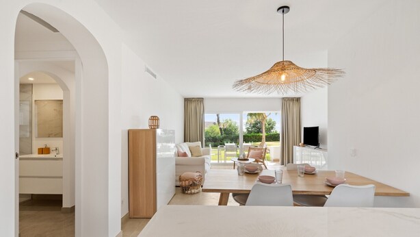 A modern living space with a dining area, a sofa, and a TV. - Apartment 'Margarita In Miraflores' with Sea Views, Shared Pool and Wi-Fi (Las Lagunas de Mijas)