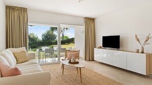 A modern living room with a sofa, coffee table, and TV on a cabinet. - Apartment 'Margarita In Miraflores' with Sea Views, Shared Pool and Wi-Fi (Las Lagunas de Mijas)