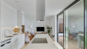 Une cuisine moderne dotée d’un îlot central, d’appareils électroménagers intégrés et d’une grande fenêtre.