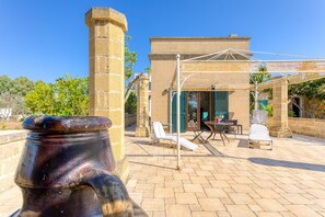 A courtyard with a stone column, outdoor seating, and a building with a covered patio.
