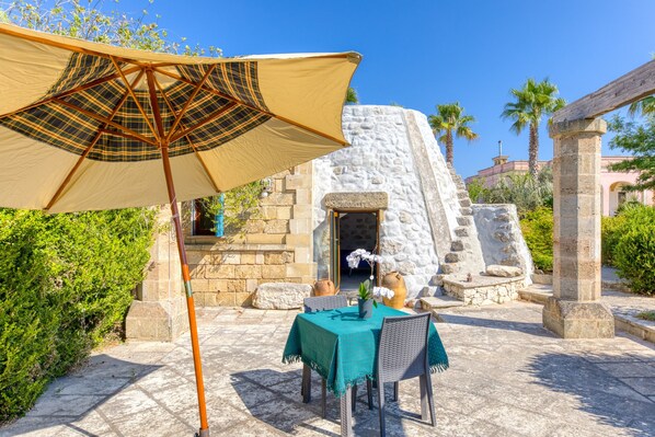 An outdoor dining area with a table, chairs, and a large umbrella.