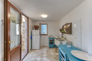 A compact kitchen with a refrigerator, a sink, and a window with a view.
