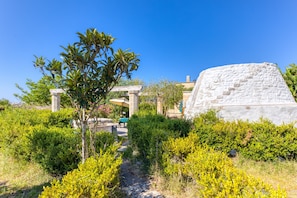A pathway leading to a stone structure with a clear blue sky above.