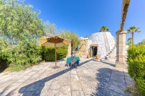 A patio with stone flooring, a table with a chair, and an umbrella.