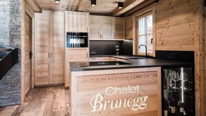 A wooden interior with a kitchen island, built-in cabinets, and a stone wall.