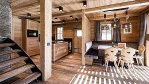A wooden interior with a kitchen, dining area, and staircase.