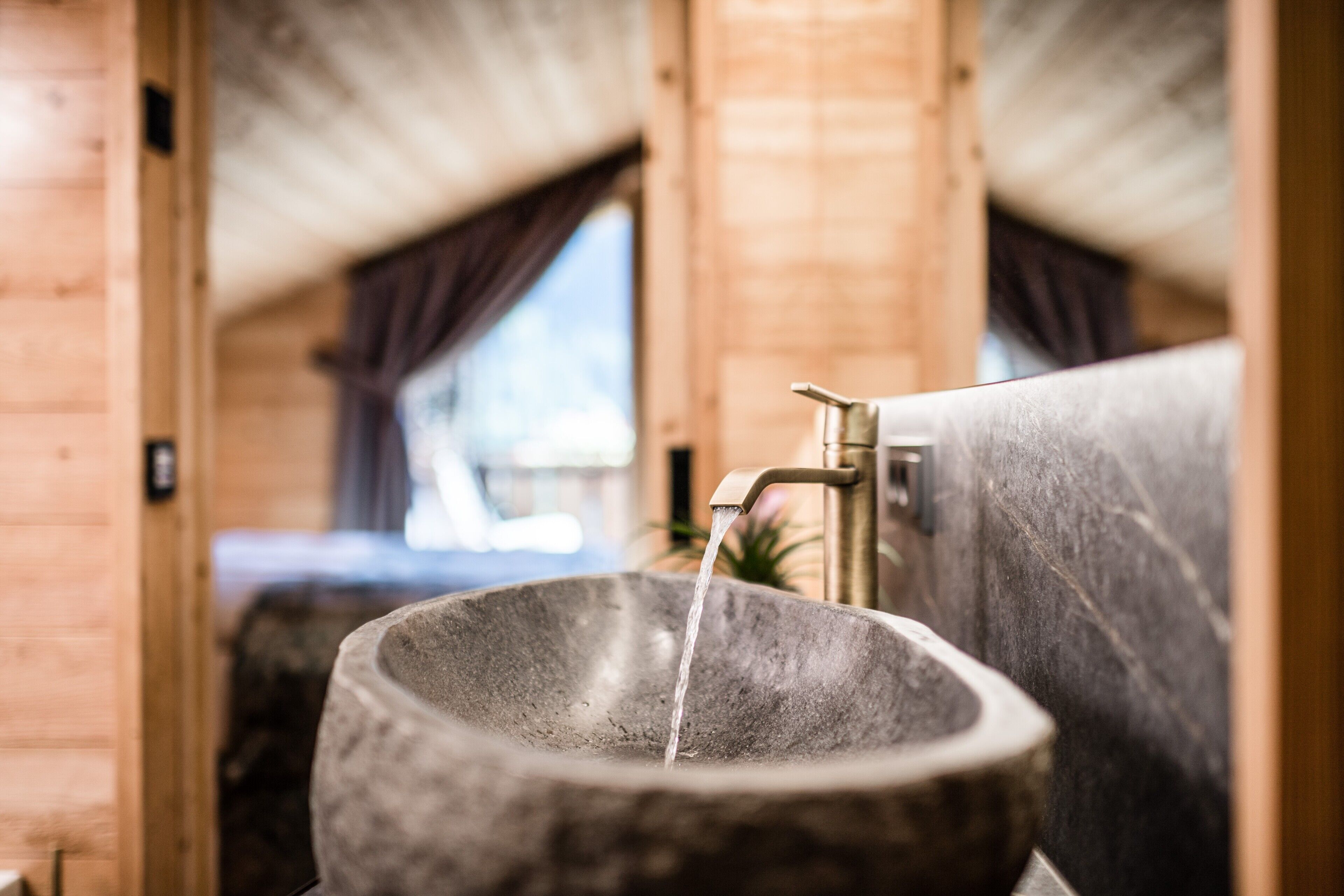 Een stenen wastafel met stromend water in een houten hut.