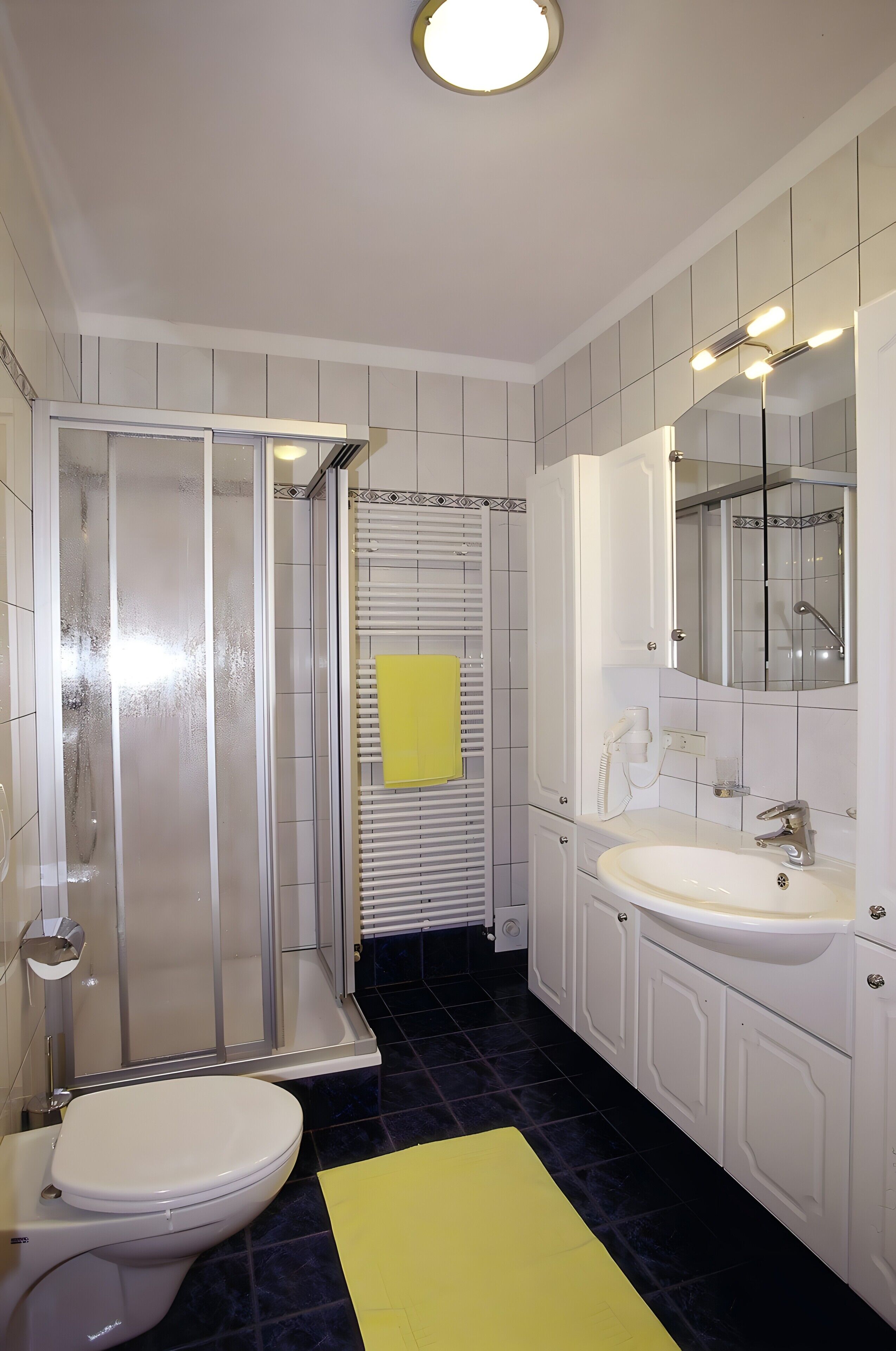 Un baño con inodoro, ducha, lavamanos y espejo.