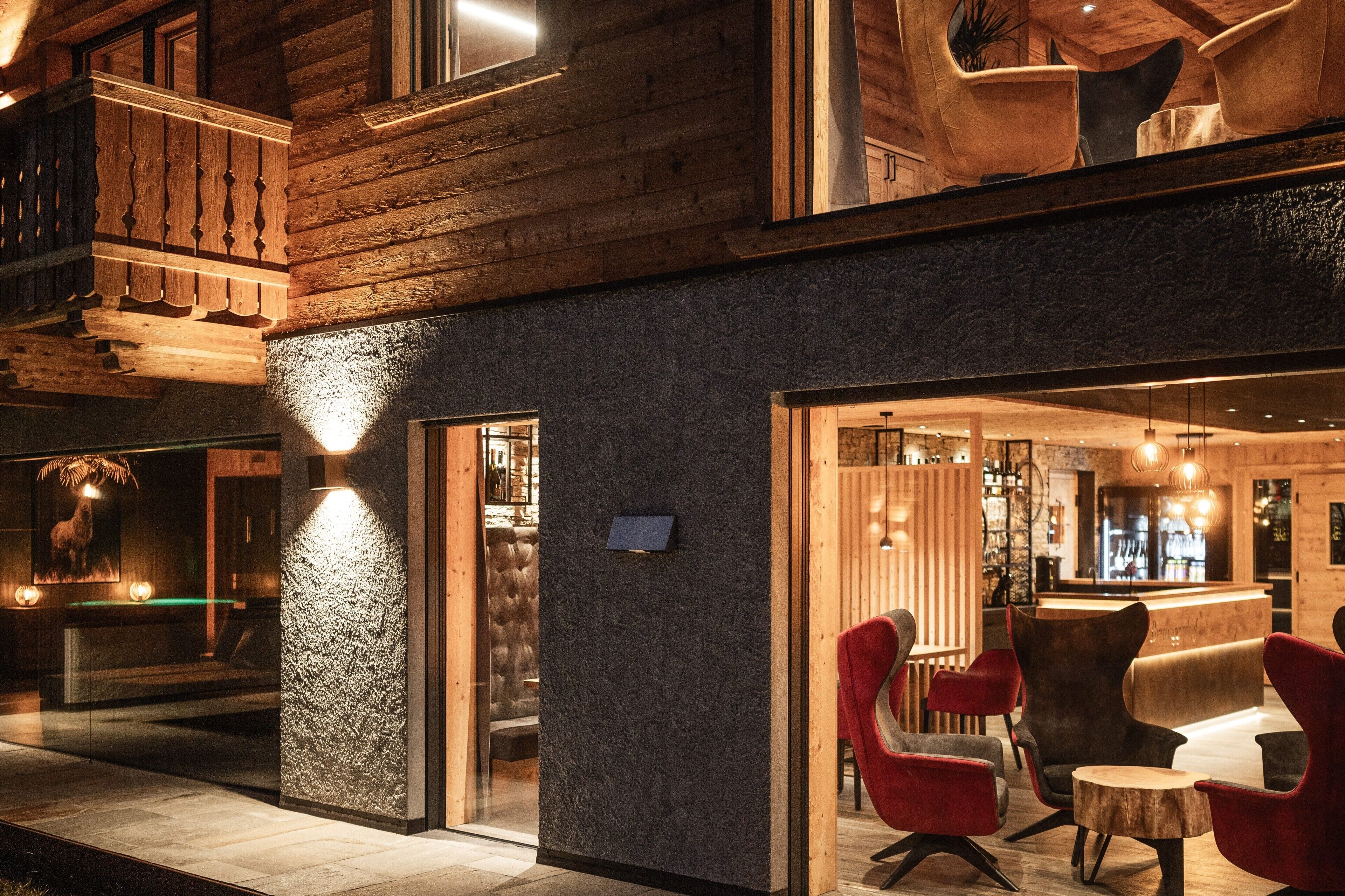 Een hotel in blokhutstijl met een bar, comfortabele zithoeken en een stenen muur.