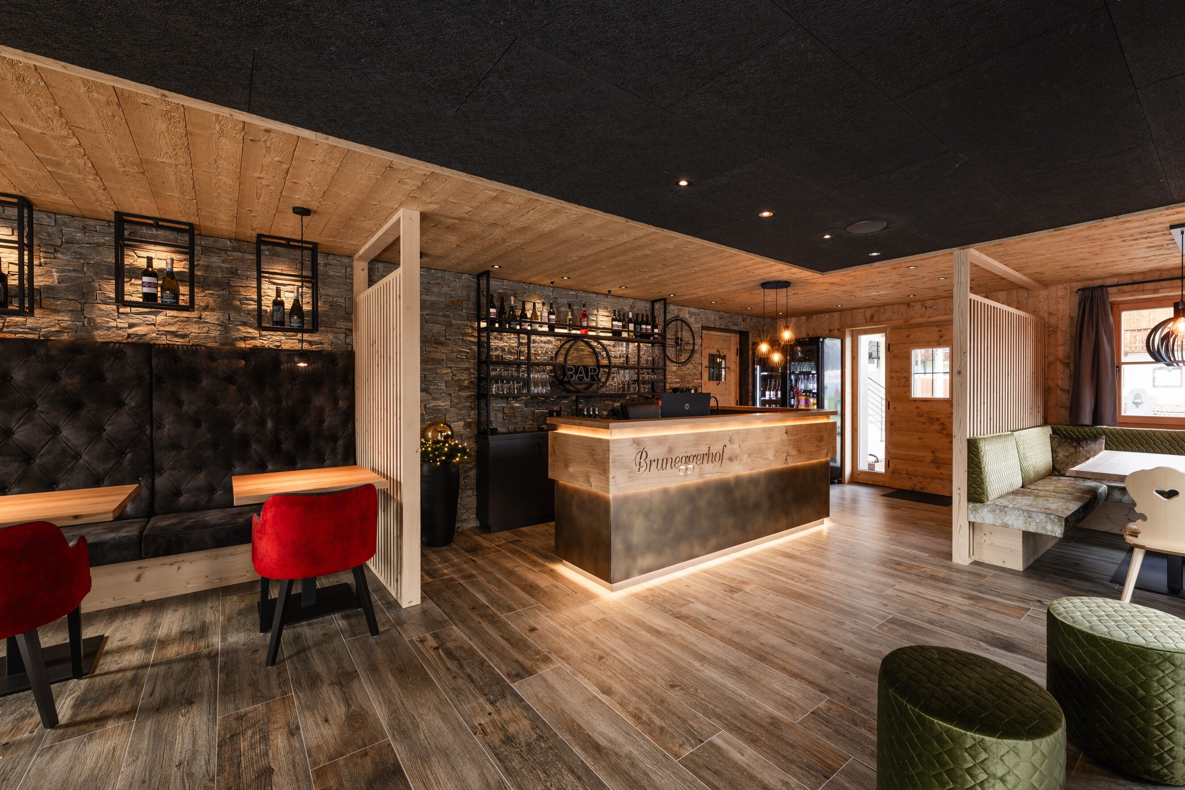 Eine Bar mit einer Holztresen, roten Stühlen und einer Steinwand.
