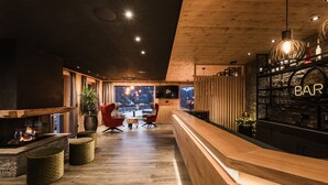 Un área de bar moderna con suelo de madera, una mesa de recepción y un ventanal con vistas al exterior.