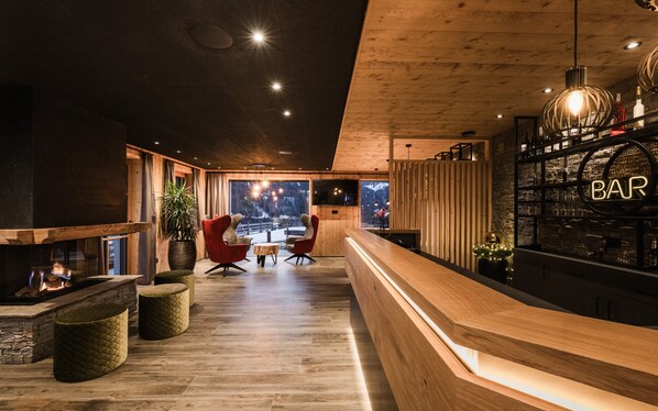 Un espace bar moderne avec un plancher en bois, un comptoir d’accueil et une grande fenêtre donnant sur l’extérieur.