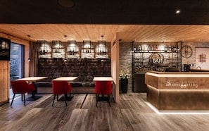 Un espace bar avec un comptoir en bois, des sièges et un mur en pierre en arrière-plan.