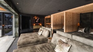 Una sala de estar moderna con un amplio sofá modular, una pared de acento de madera y una chimenea.