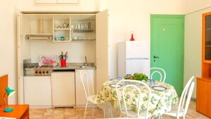 Uma cozinha compacta com área de jantar, uma porta verde e uma geladeira pequena.