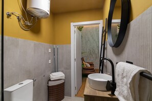 Ein Badezimmer mit Toilette, Waschbecken, Handtuchhalter und Duschbereich.