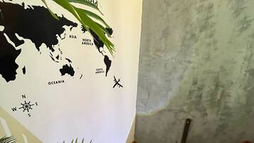 Una escalera con barandilla de madera, un mapa mundial en la pared y una planta en maceta.