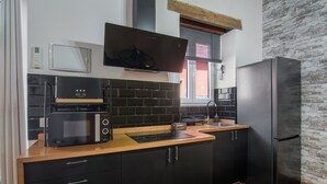 A modern kitchen with black cabinets, a microwave, a toaster, and a refrigerator.