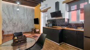 A compact kitchen with a built-in microwave, a flat-screen TV, and a refrigerator.