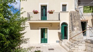 A building with a green door, a balcony with flower boxes, and a stone staircase. - Room 'Lì' with Mountain View, Wi-Fi and Air Conditioning (Scicli)